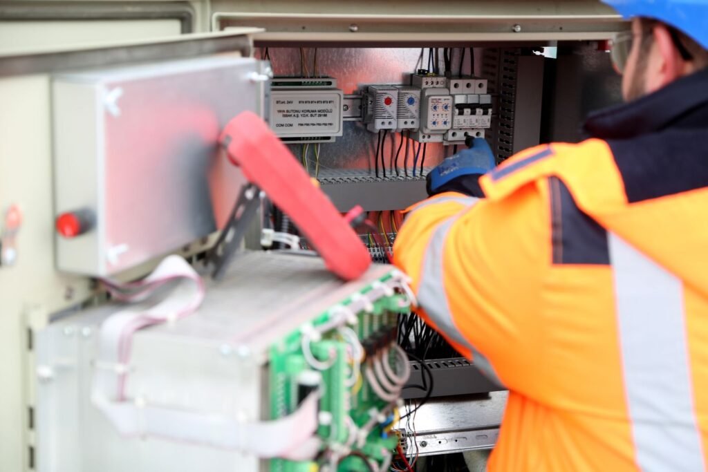 Electricista con chaleco de alta visibilidad trabajando en un tablero eléctrico